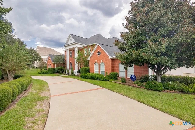a view of a house with a big yard plants and large trees