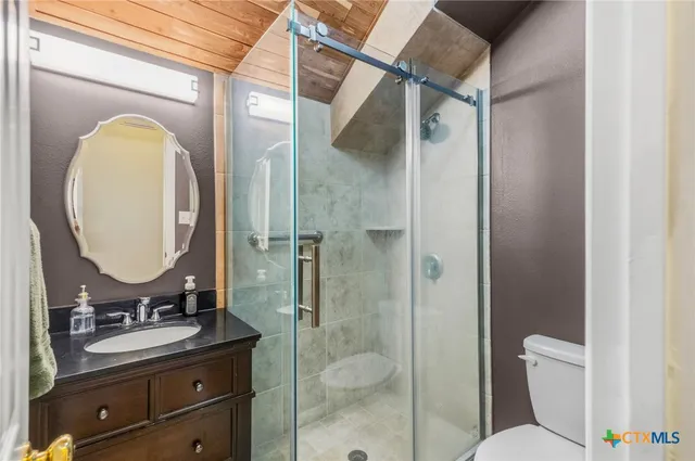 a view of a white building with a large tree and flower plants