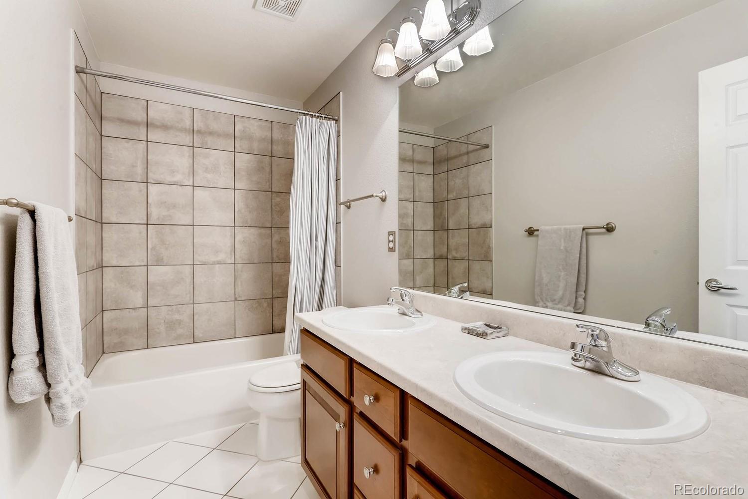 10825 Towerbridge Road Highlands Ranch, CO 80130 - Photo 19 of 24 a bathroom with a sink a toilet a mirror a bathtub and shower
