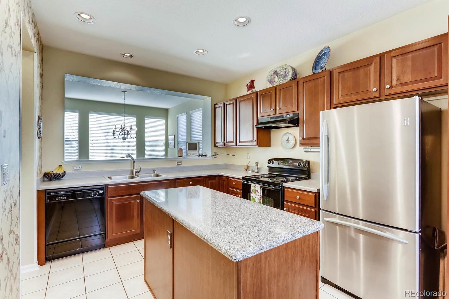 10825 Towerbridge Road Highlands Ranch, CO 80130 - Photo 9 of 24 a kitchen with granite countertop a sink stove and refrigerator