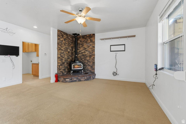 1001 Pine Valley Road Pine Valley, UT 84781 - Photo 13 of 49 Unfurnished living room with ceiling fan, light carpet, and a wood stove