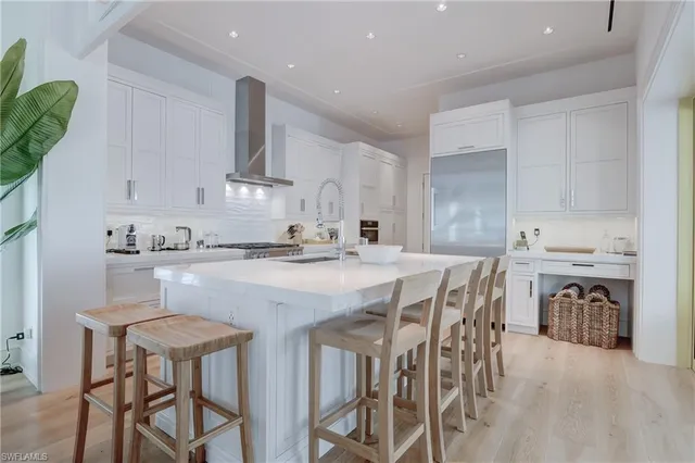 a kitchen with stainless steel appliances kitchen island granite countertop a table chairs sink and cabinets