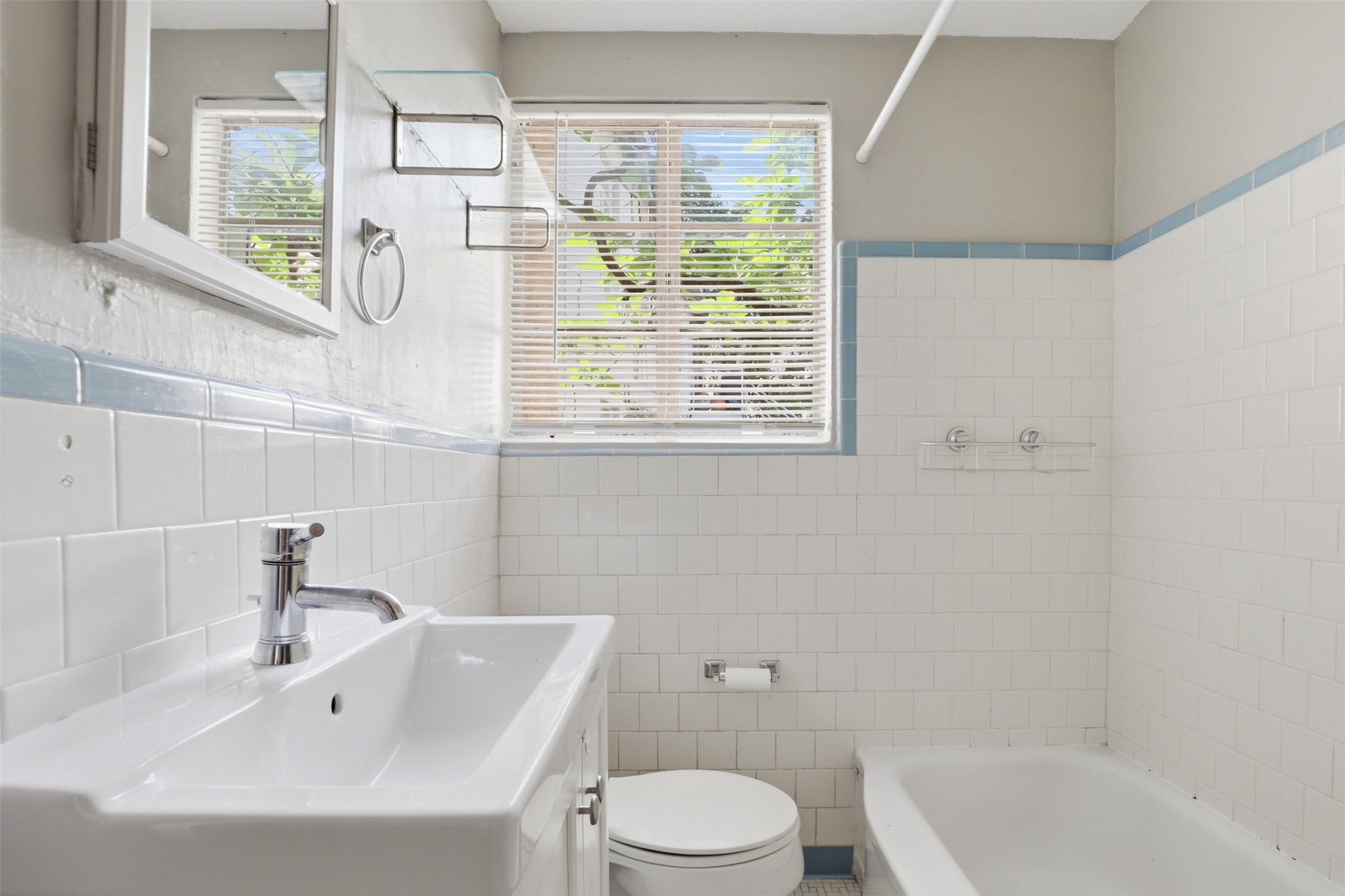 3901 Wrightwood Road, Unit A Austin, TX 78722 - Photo 9 of 11 Bathroom featuring white subway tile walls with blue trim, a window with blinds, a white vanity with an integrated sink and chrome faucet, and a white bathtub.