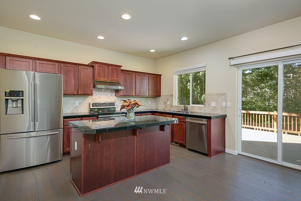 357 Field Place Northeast Renton, WA 98059 - Photo 7 of 26 a kitchen with granite countertop a stove top oven a sink dishwasher a refrigerator and cabinets with wooden floor