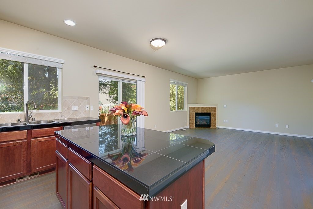 357 Field Place Northeast Renton, WA 98059 - Photo 8 of 26 a kitchen with stainless steel appliances granite countertop a sink dishwasher a stove a dining table and chairs with wooden floor