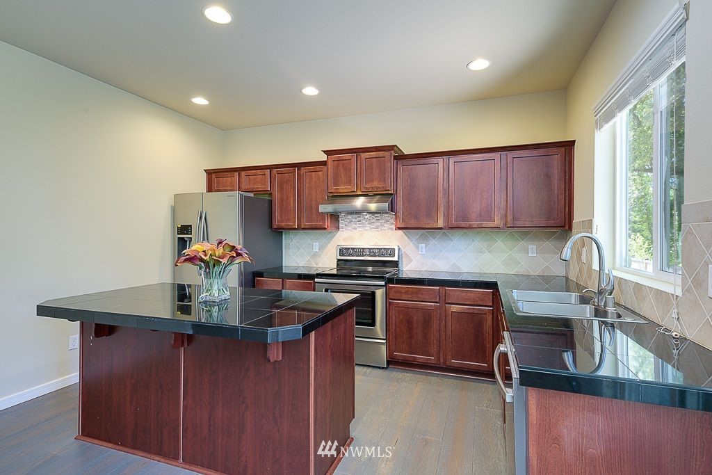 357 Field Place Northeast Renton, WA 98059 - Photo 9 of 26 a kitchen with kitchen island granite countertop a sink stove and cabinets