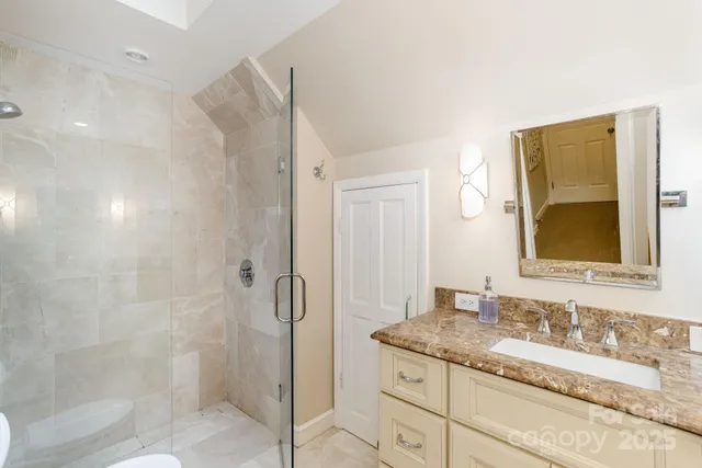 a bathroom with a granite countertop sink a mirror and shower
