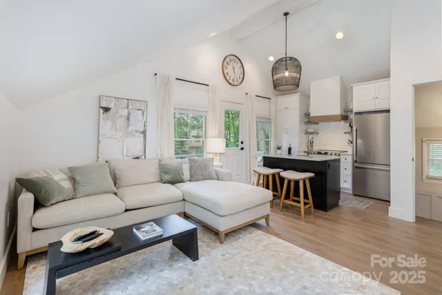 a living room with kitchen island furniture a chandelier and a large window