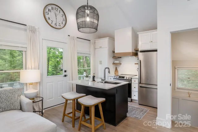 a kitchen with stainless steel appliances granite countertop a table chairs a sink and a large window