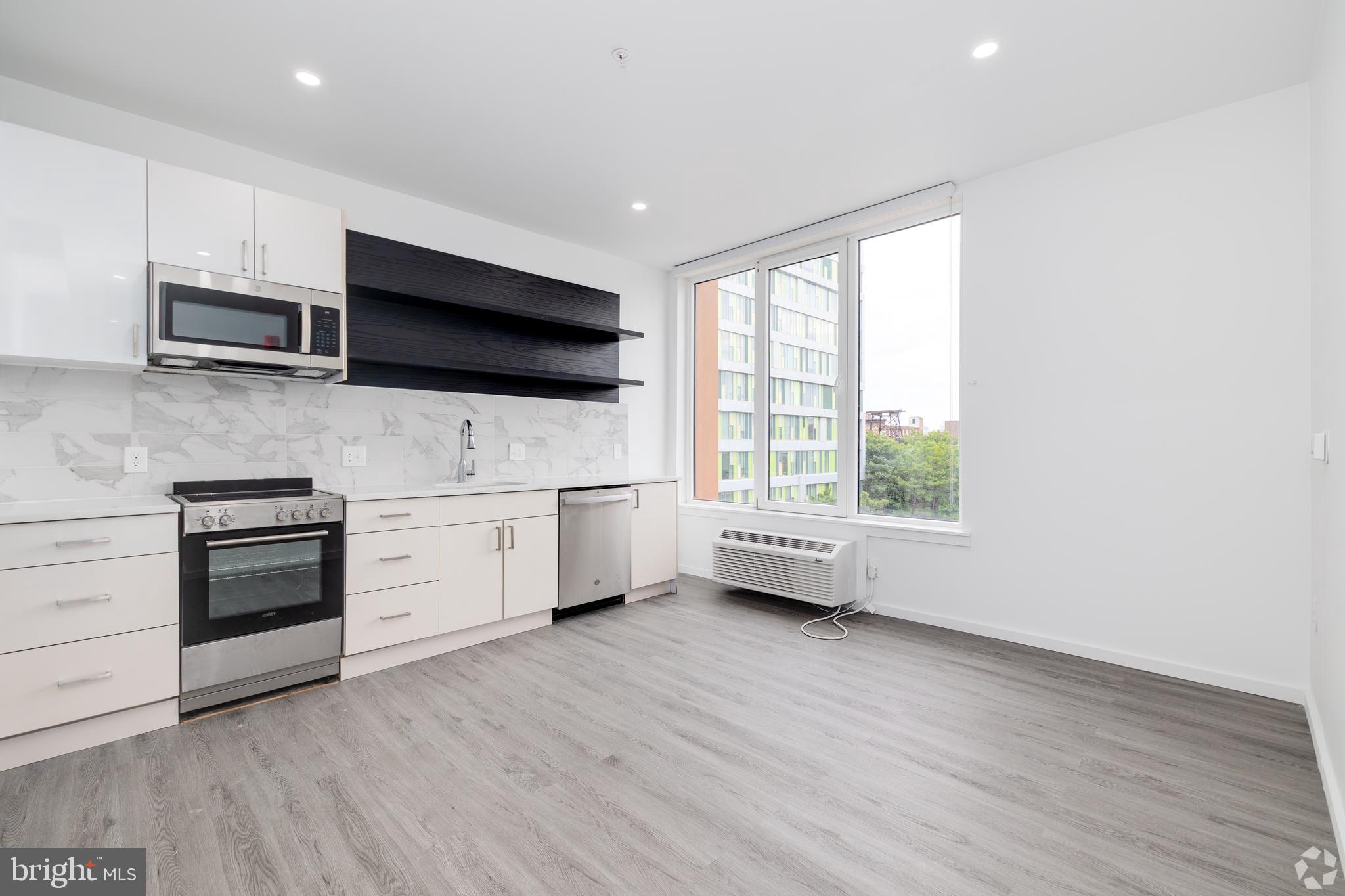 1201 Vine Street, Unit 1 Philadelphia, PA 19107 - Photo 15 of 32 a kitchen with stainless steel appliances a white stove top oven a sink dishwasher and a microwave with wooden floor