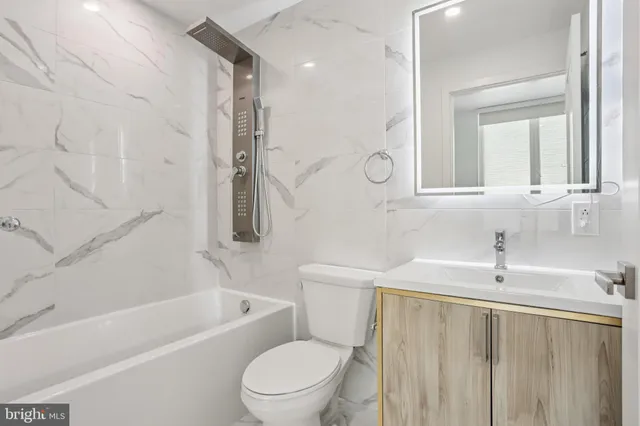 a bathroom with a toilet a sink a mirror a bathtub and shower