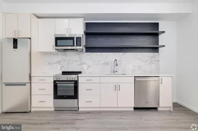 a kitchen with stainless steel appliances white cabinets and a wooden floor