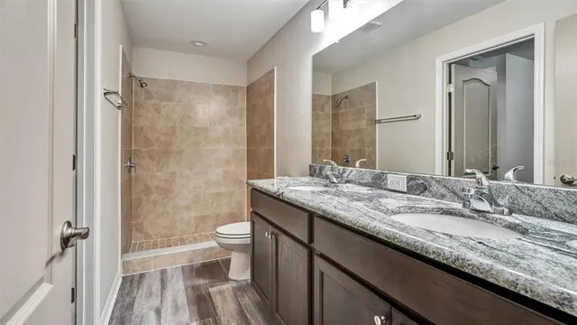 a bathroom with a granite countertop sink a toilet a shower and a mirror