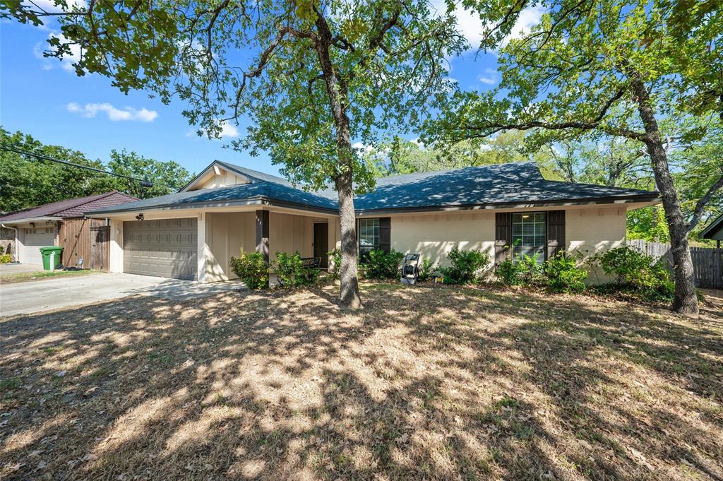 608 Ridgewood Circle Hurst, TX 76054 - Photo 4 of 38 Single-story stucco exterior with a dark-shingle roof, featuring shuttered windows, an attached two-car garage, and a covered entry