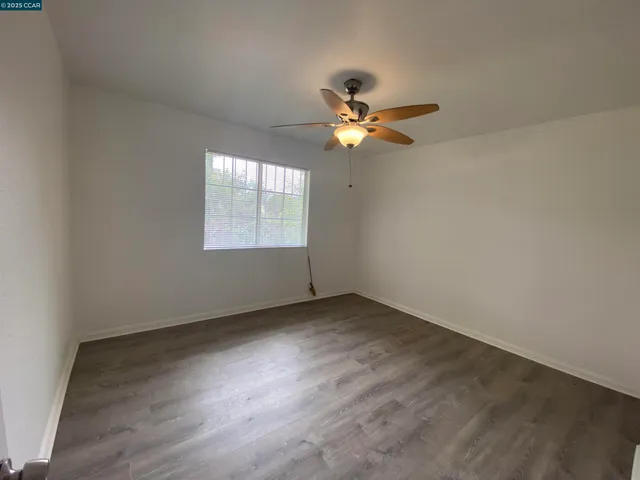 an empty room with a window and ceiling fan