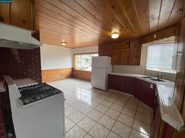 a kitchen with granite countertop a stove a sink dishwasher and a refrigerator