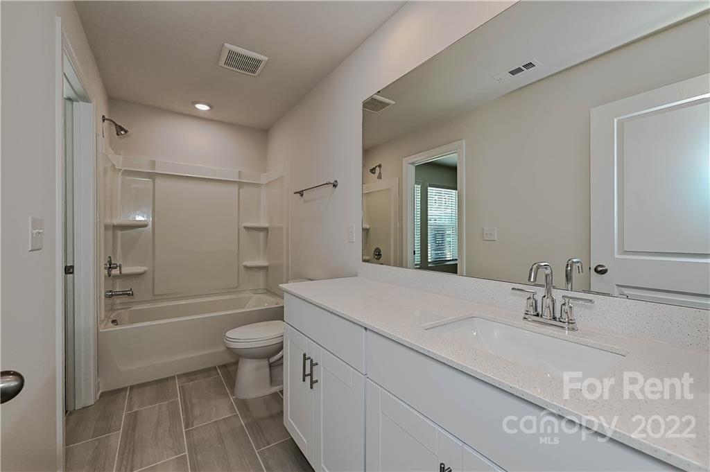 3534 Auburn Curb Road Charlotte, NC 28217 - Photo 10 of 11 a bathroom with a granite countertop sink a toilet a mirror and shower