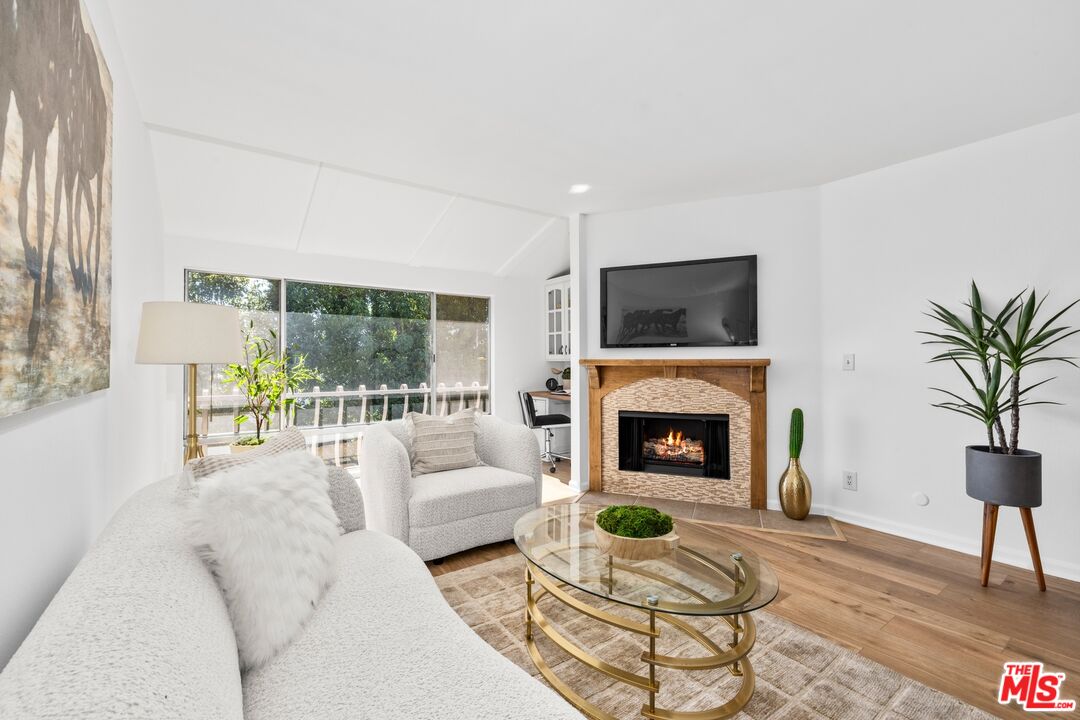12720 Burbank Boulevard, Unit 318 Valley Village, CA 91607 - Photo 2 of 12 a living room with furniture a fireplace and a floor to ceiling window