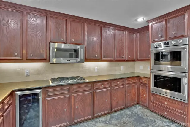 a kitchen with granite countertop wooden cabinets and stainless steel appliances