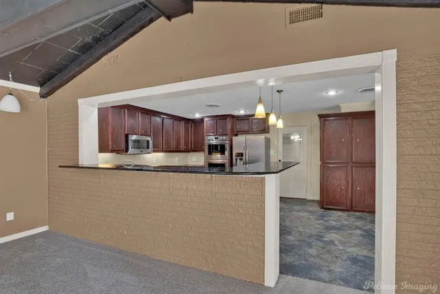 a view of kitchen with kitchen island and stainless steel appliances