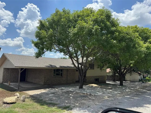 a view of a house with a tree next to a yard