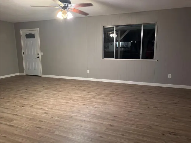a view of an empty room with window and wooden floor