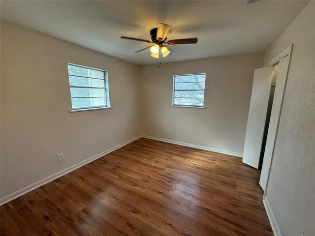 a view of empty room with wooden floor and fan