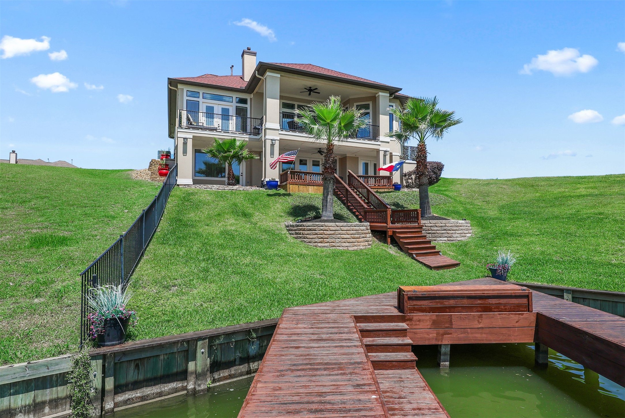 10896 Decatur Street Willis, TX 77318 - Photo 47 of 50 Experience luxury and tranquility in this stunning waterfront property, featuring a modern two-story home with expansive balconies, large windows, and a beautifully landscaped yard with palm trees leading to a private dock for perfect lakeside living.