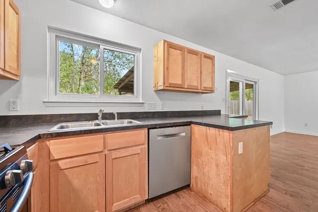 a kitchen with granite countertop wooden cabinets a sink and a window