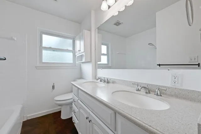 a bathroom with a granite countertop sink a toilet and a mirror