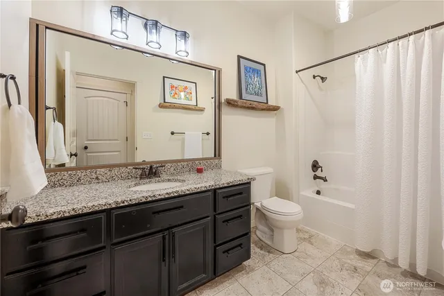 a bathroom with a granite countertop sink toilet and mirror