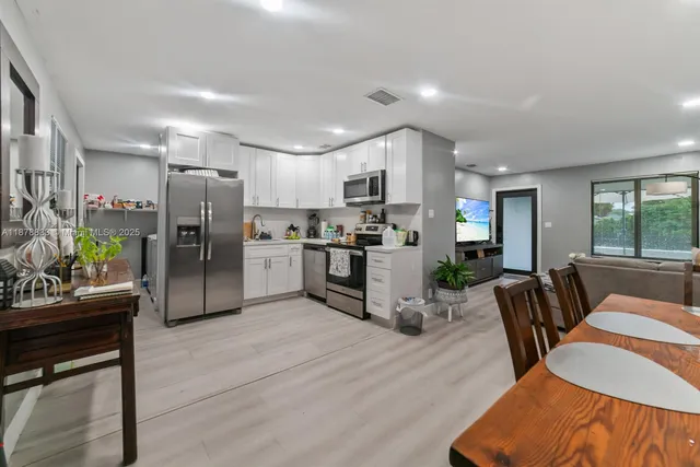 a kitchen with stainless steel appliances wooden floor and a refrigerator