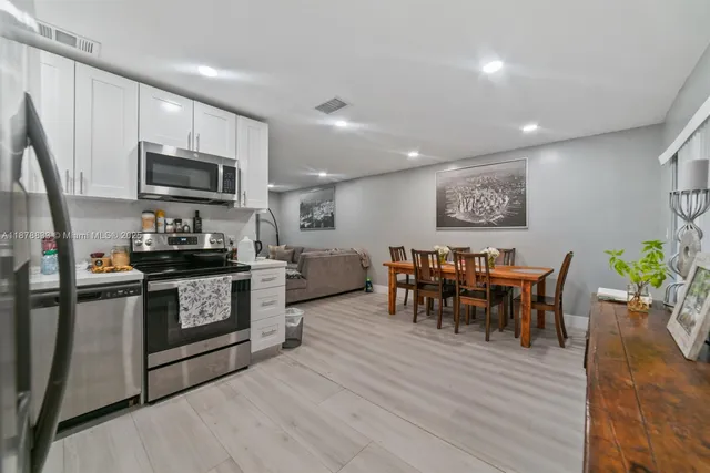 a kitchen with stainless steel appliances granite countertop a stove top oven a sink a dining table and chairs