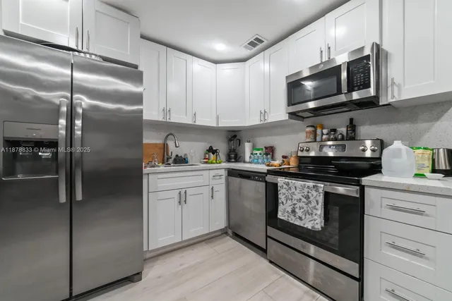 a kitchen with stainless steel appliances granite countertop a refrigerator a stove top oven a sink and cabinets