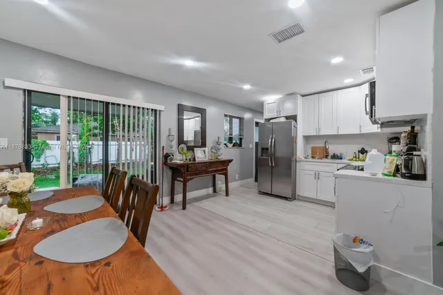 a kitchen with stainless steel appliances granite countertop a table chairs refrigerator and a sink