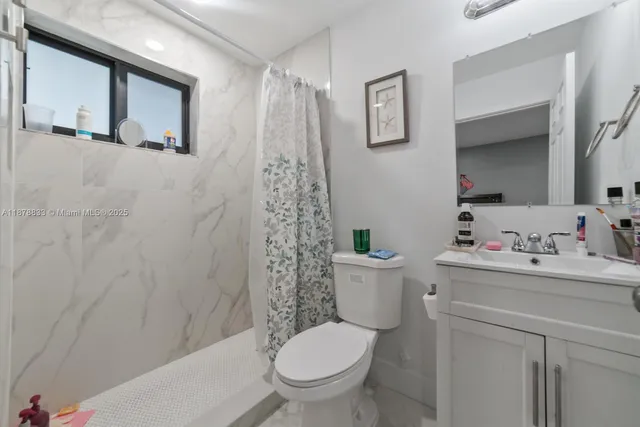 a white toilet sitting next to a bathroom sink and a shower