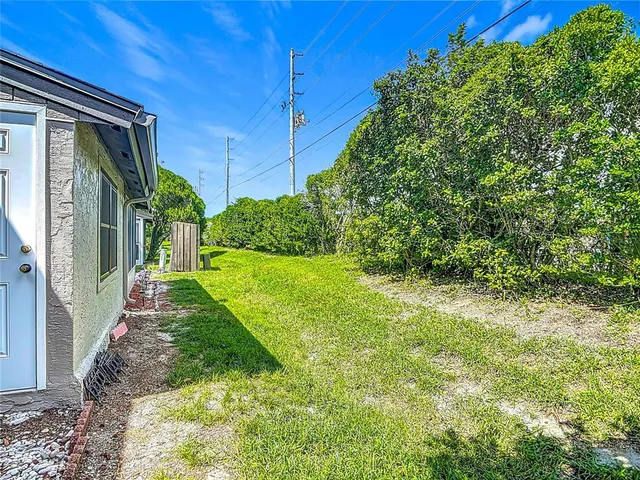 a view of a house with a yard plants and large tree