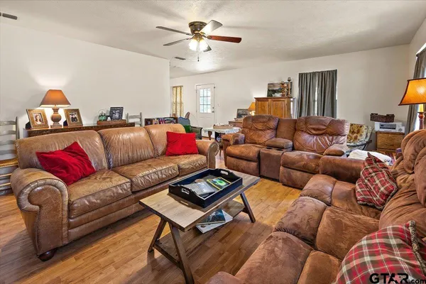 a living room with furniture a ceiling fan a lamp and a window