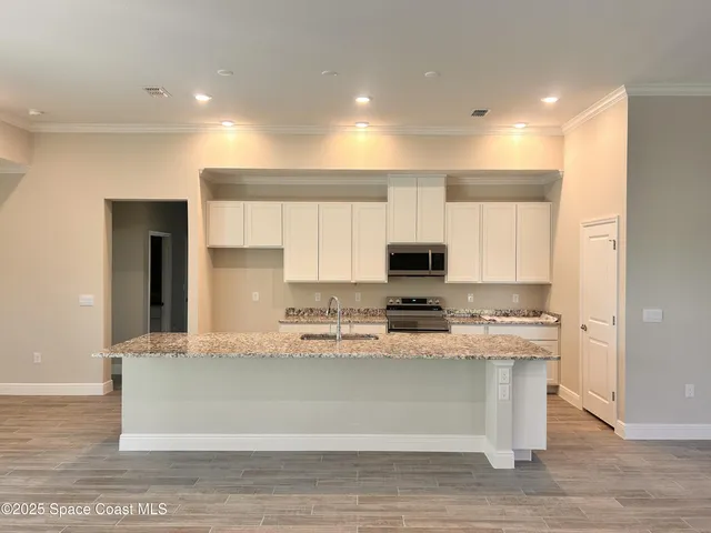 a large white kitchen with kitchen island granite countertop a sink a counter top space and cabinets