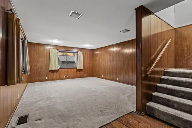 a view of an empty room with stairs and wooden floor