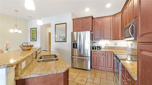 a kitchen with stainless steel appliances granite countertop a refrigerator a stove and a sink