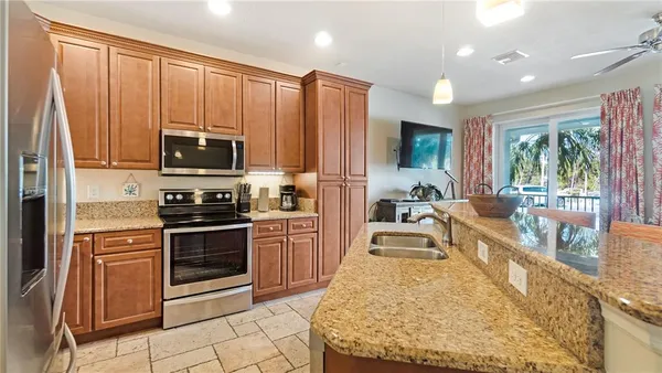 a large kitchen with kitchen island granite countertop wooden cabinets a stove a sink and a refrigerator