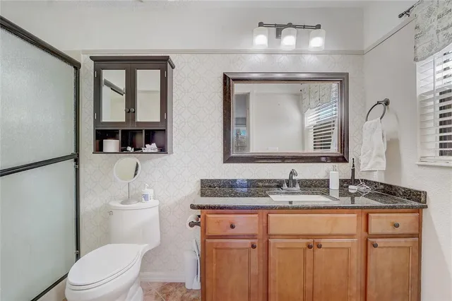 a bathroom with double vanity sink a mirror and a toilet