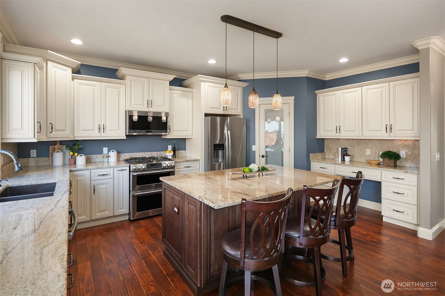 22632 Southeast 281st Street Maple Valley, WA 98038 - Photo 7 of 24 a kitchen with stainless steel appliances granite countertop a stove top oven a refrigerator a sink and a dining table with wooden floor