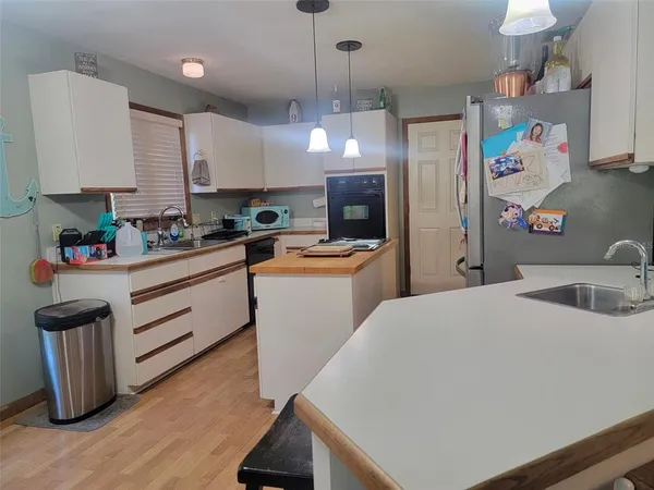a kitchen with a sink a stove a refrigerator and chairs