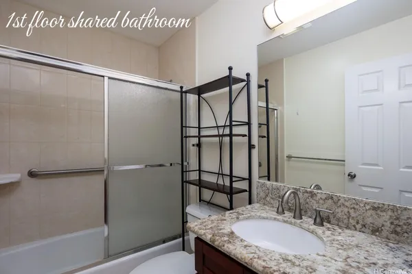 a bathroom with a granite countertop shower sink and mirror