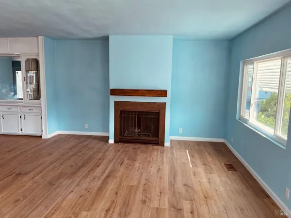 a view of empty room with wooden floor and fireplace