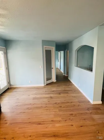 a view of an empty room with window and wooden floor