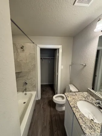 a bathroom with a granite countertop sink a toilet and shower