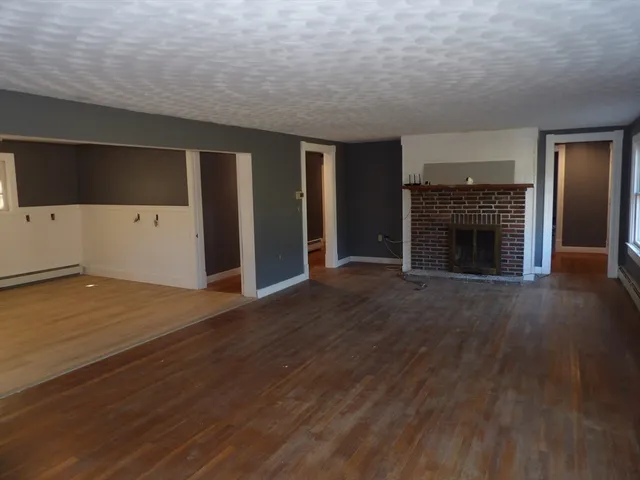 an empty room with wooden floor fireplace and windows